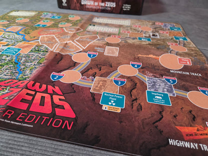 Board game mat with 'Dawn of the Zeos' branding on a gray surface