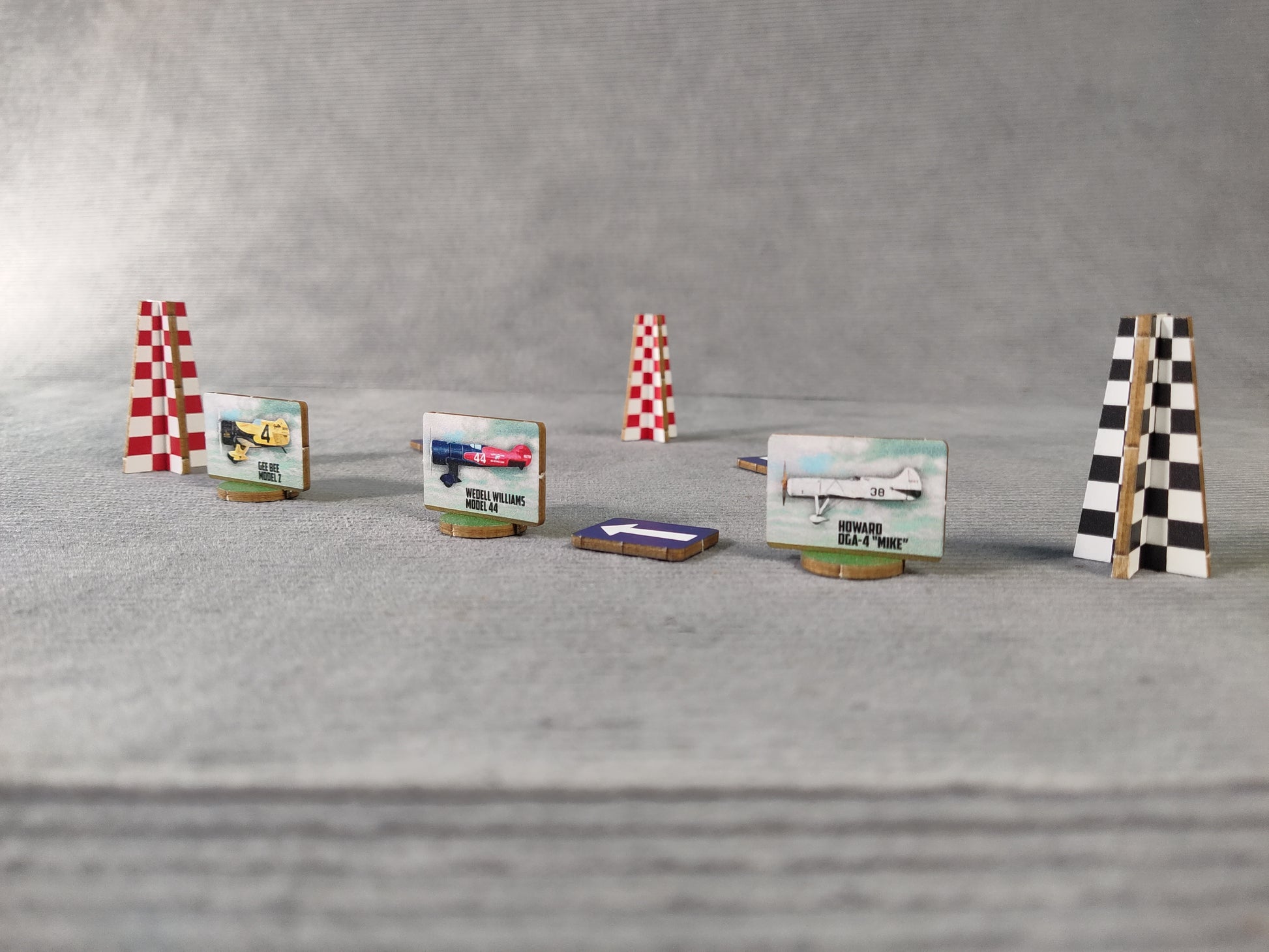 Model race track with planes and checkered flags on a gray surface.
